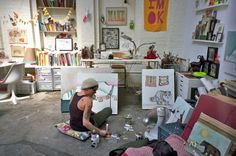 a woman sitting on the floor in an art studio