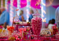 candy bar with pink and white candies in glass vases on table at party