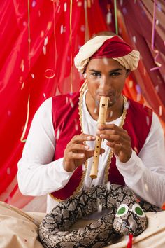 a man is sitting on the floor playing a flute