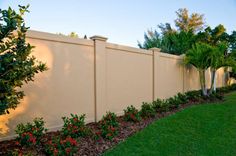 a white fence with red flowers in the foreground and green grass on the other side