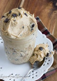 a glass jar filled with frosting and chocolate chips on top of a white plate