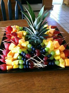 a fruit platter with pineapples, grapes, strawberries, and pineapple on skewers