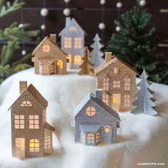 small houses are lit up in the snow with christmas trees around them and on top of it