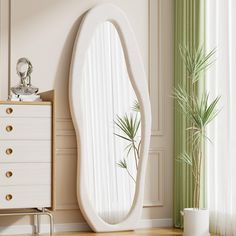 a mirror sitting on top of a wooden floor next to a dresser and potted plant