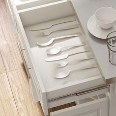 an open drawer in a kitchen filled with white utensils