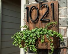 a house number sign on the side of a brick building with ivy growing in it