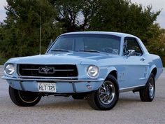 an old blue mustang parked in a parking lot