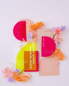 three different colored cards on top of each other next to some flowers and paper circles