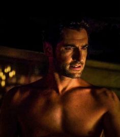 a shirtless man standing in the dark with his hands on his hips and looking at the camera