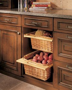 two wicker baskets with potatoes in them sit on the bottom shelf of a kitchen cabinet