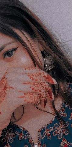 a woman holding her hands to her face with henna painted on it's body