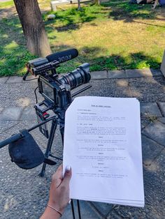 a person holding a piece of paper in front of a camera on a tripod