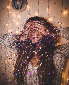 a man with long hair standing in front of a mirror covered in confetti