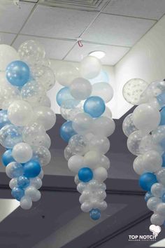 blue and white balloons are hanging from the ceiling