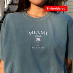 🌴 "Miami Beach Florida USA embroidered on a comfort colors tee. Designed for everyone who seeks the sun, sand, and sea, our Miami Beach T-Shirt is a unisex comfort colors tee, making it an ideal choice for both men and women. The classic t-shirt offers a versatile and relaxed fit, perfect for casual outings or beachside adventures.  *SIZES ARE UNISEX* -I'd suggest sizing up for a more relaxed fit, or your usual size for a more fitted look -Model is 5'3 and wearing a large in ice blue * 100% rin Beach Embroidered Short Sleeve T-shirt, Embroidered Short Sleeve Beach T-shirt, Embroidered Short Sleeve T-shirt For Beach, Summer Custom Embroidered Crew Neck T-shirt, Custom Embroidered Relaxed Fit T-shirt For Summer, Custom Embroidered Summer T-shirt, Custom Embroidered Graphic Tee For Summer, Graphic Tee With Custom Embroidery For Summer, Custom Embroidery Graphic Tee For Summer