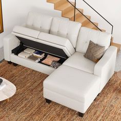 a living room with a white couch and coffee table on the floor next to stairs