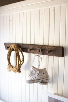 a pair of shoes hanging from a wooden shoe rack on a white wall with rope