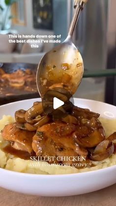 a spoon scooping some food out of a white bowl on top of mashed potatoes