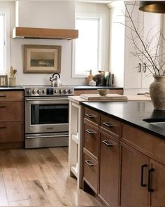 a kitchen with wooden cabinets and stainless steel stove top oven in the center, surrounded by wood flooring