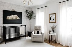 a baby's room with a crib, rocking chair and painting on the wall