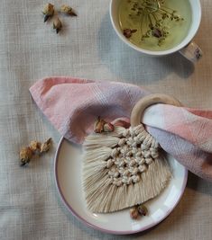 a white plate topped with a tassel next to a cup of tea and napkin