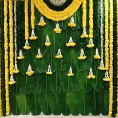 an arrangement of yellow flowers and green leaves on the side of a building with a white face