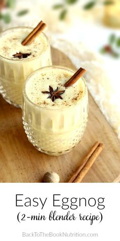 two glasses filled with eggnog on top of a wooden cutting board next to cinnamon sticks