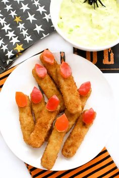 some food is on a white plate near a bowl of dip and a black and orange napkin