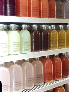 many bottles of liquid are lined up on shelves