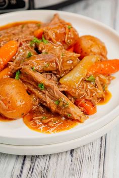 a white plate topped with meat and carrots next to an instant pressure cooker