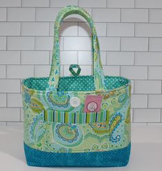 Paisley Small Tote Bag   Just the right size to carry your essentials and look stylish doing so.  Make a great gift unique and stylish Made from quality 100% Cotton Fabric with a firm interfacing to keep its shape. This item is READY to ship. Fabric Pattern may vary from the photo. Approximately     8" High   x 10" Long    x 4  1/2" Deep Has two cotton handles 1" wide and an 8" drop for over the shoulder look Has an open front slip pocket    5  1/2" Long   x 4" High Open Top with a button loop closure  4  inside slip pockets 2 on each side    4"  x  4" All My items Are Made In A Smoke, Pet and Virus Free Home Looking for something Special  I make Unique handmade Totes, Purses, Pouches, Coin Purses, Table Runners and Quilts Tote Bags With Pockets As Gifts, Rectangular Bag With Snap Closure As Gift, Pouch Bags With Snap Closure As Gift, Green Bag With Cell Phone Pocket As Gift, Green Bag With Cell Phone Pocket For Gift, Gift Pouch Bag With Snap Closure, Green Rectangular Bag With Snap Closure, Green Everyday Bag With Snap Closure, Everyday Green Bag With Snap Closure