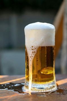 a glass of beer sitting on top of a wooden table