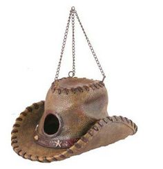 a brown hat hanging from a chain on top of a white wall with a black hole in the center