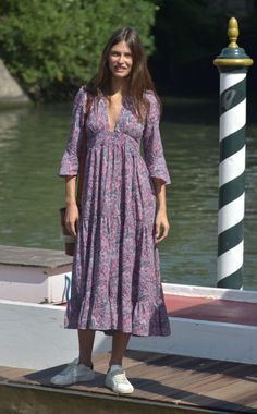 a woman in a dress standing on a dock