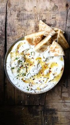 a bowl filled with hummus and pita bread on top of a wooden table