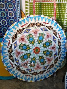 several colorful plates sitting on the ground next to each other in front of a wall