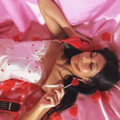 a woman laying on top of a bed next to a cell phone with hearts all over it