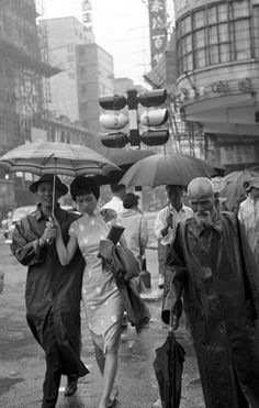 black and white photograph of people walking down the street with umbrellas over their heads