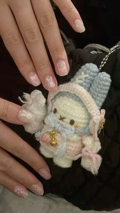 a woman's hands with manicured nails holding a small stuffed animal