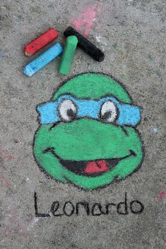 a chalk drawing of a teenaged ninja turtle on the ground with crayons