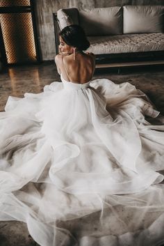 a woman in a wedding dress sitting on the floor with her back to the camera