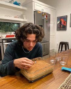 a man sitting at a kitchen table with a bowl of food in front of him