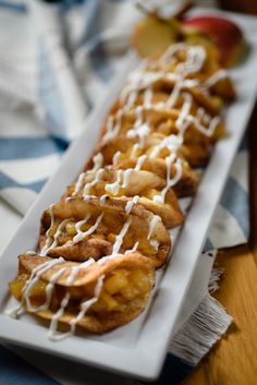 a white plate topped with mini apple pie tacos covered in icing and drizzled