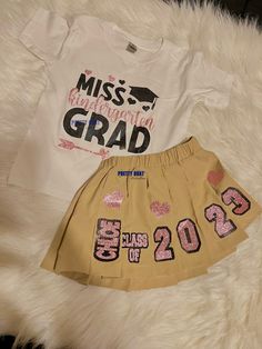 Graduate in style with this custom Pre-K & Kindergarten Grad Skirt Set! Shirts or Sweatshirts can be done in your requested color, if available. Skirts are available in black or white, however, if you are requesting a different color skirt, please contact us before ordering.Complete Custom You can choose a design not pictured and work with our design team to bring it to life! Please ensure you send us the following information when ordering:1. School Name2. School Colors3. Skirt and Sweatshirt C Fitted T-shirt For School In Spring, Fitted White Skirt For Cheerleading, Fitted Cotton Skirt For Cheerleading, Casual Cotton Skirt For Cheerleading, Prek Outfit Girl, Casual Cotton Cheerleading Skirt, Sweater And Skirt Graduation Pictures, White Cotton School Spirit Sets, First Day Of School Outfit Uniform Skirt