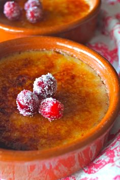 two orange bowls filled with pudding on top of a red and white table cloth covered in powdered sugar