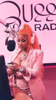 a woman with red hair wearing headphones is looking at her cell phone while standing in front of a microphone