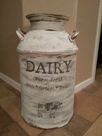 an old milk can with dairy labels painted on it sitting on the floor in front of a wall