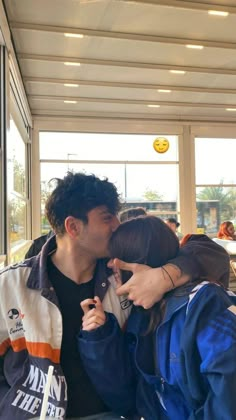 a man kissing a woman on the cheek in front of a window at an airport