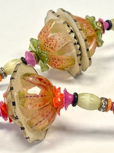 two glass beaded bracelets sitting on top of a white table next to each other