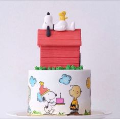 a three tiered cake decorated with snoopy and charlie the pooh on top